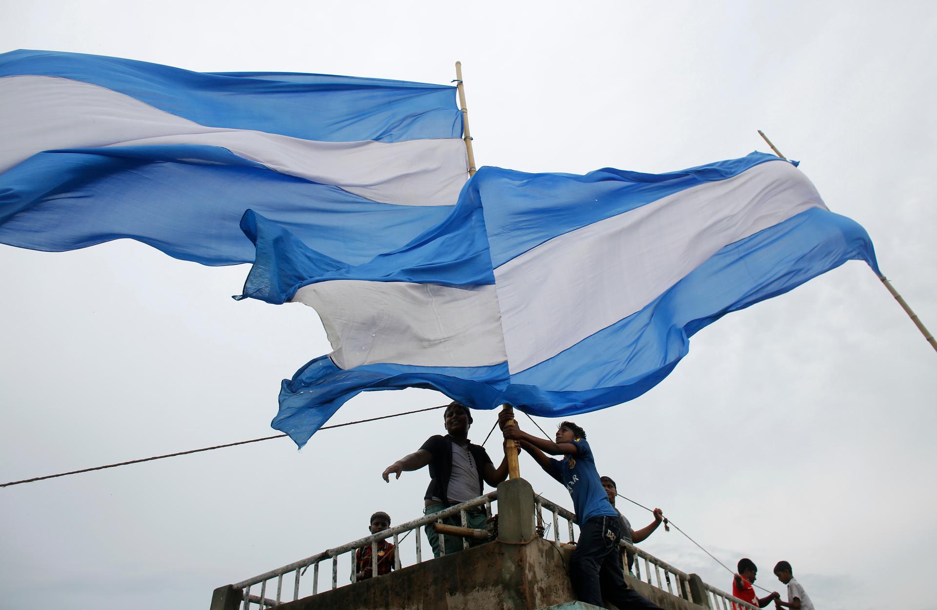 Children attach flags of 2014 World Cup participant Argentina to the top of a building in Dhaka May 28, 2014. Millions of Bangladeshi football fans mostly support the national football teams of Argentina and Brazil.