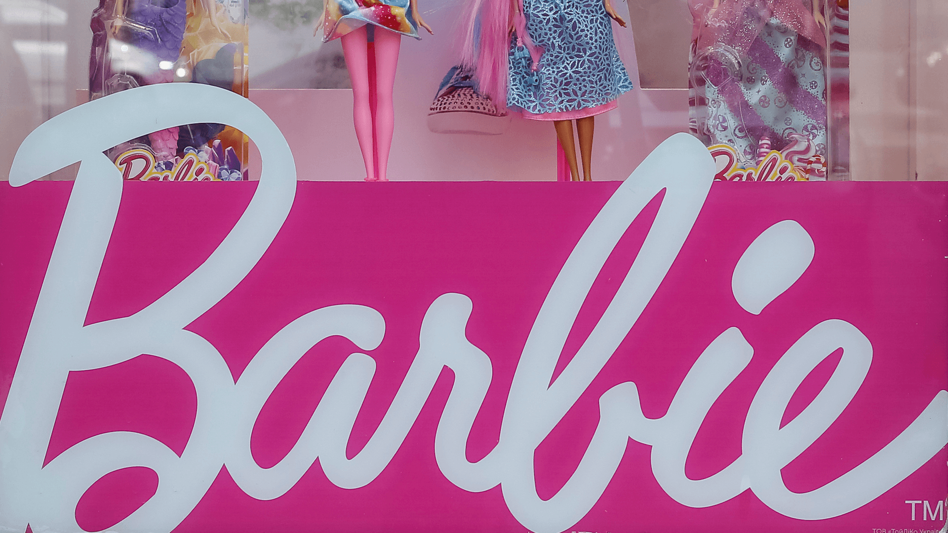 Barbie dolls are seen in a window of a toy store.