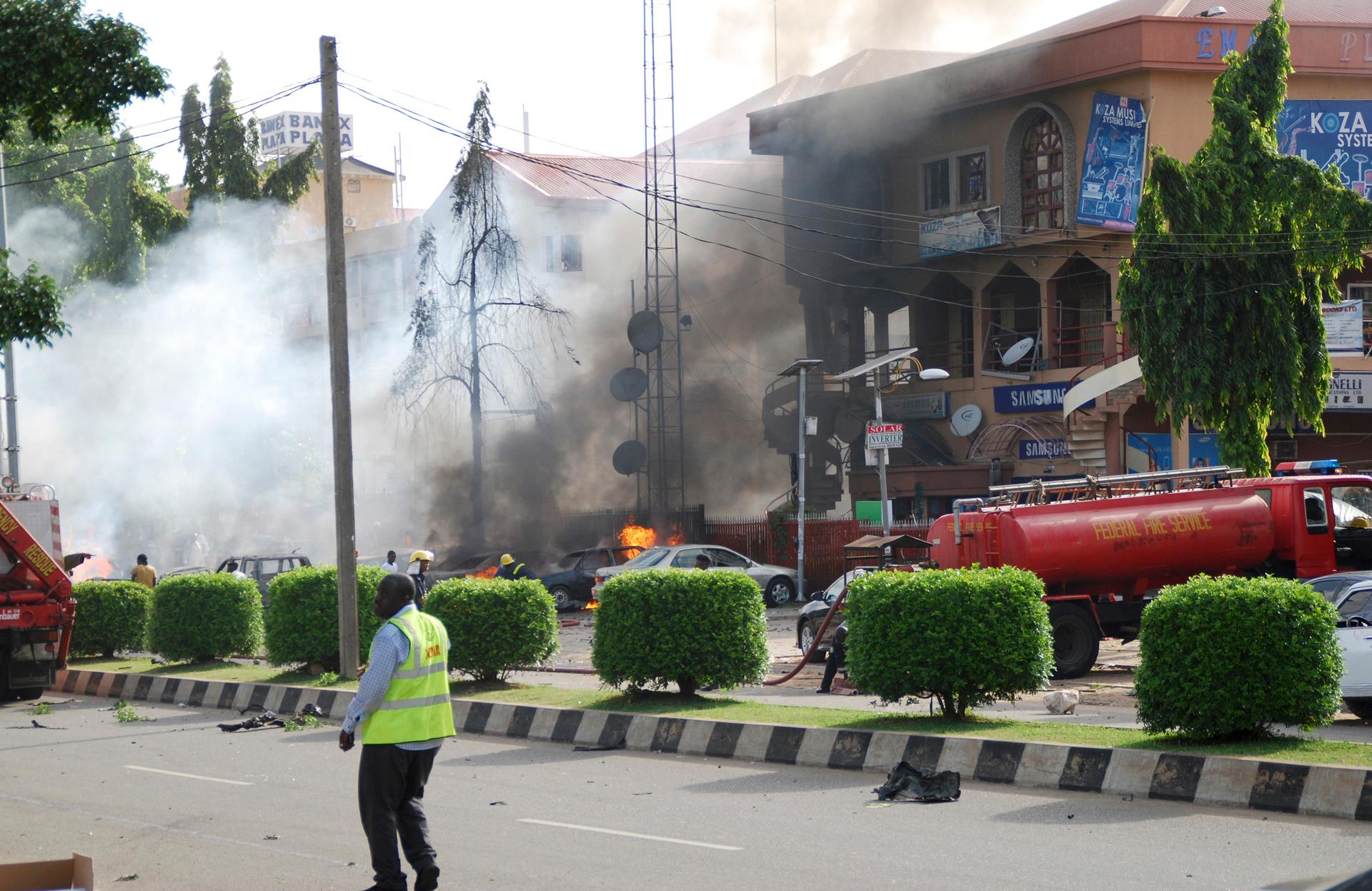 An emergency responder walks on a road near fire engines working to put a fire after a blast in the Wuse 2 neighbourhood of Abuja, June 25, 2014. At least 21 people were killed when a suspected bomb tore through the crowded shopping district in the Nigeri
