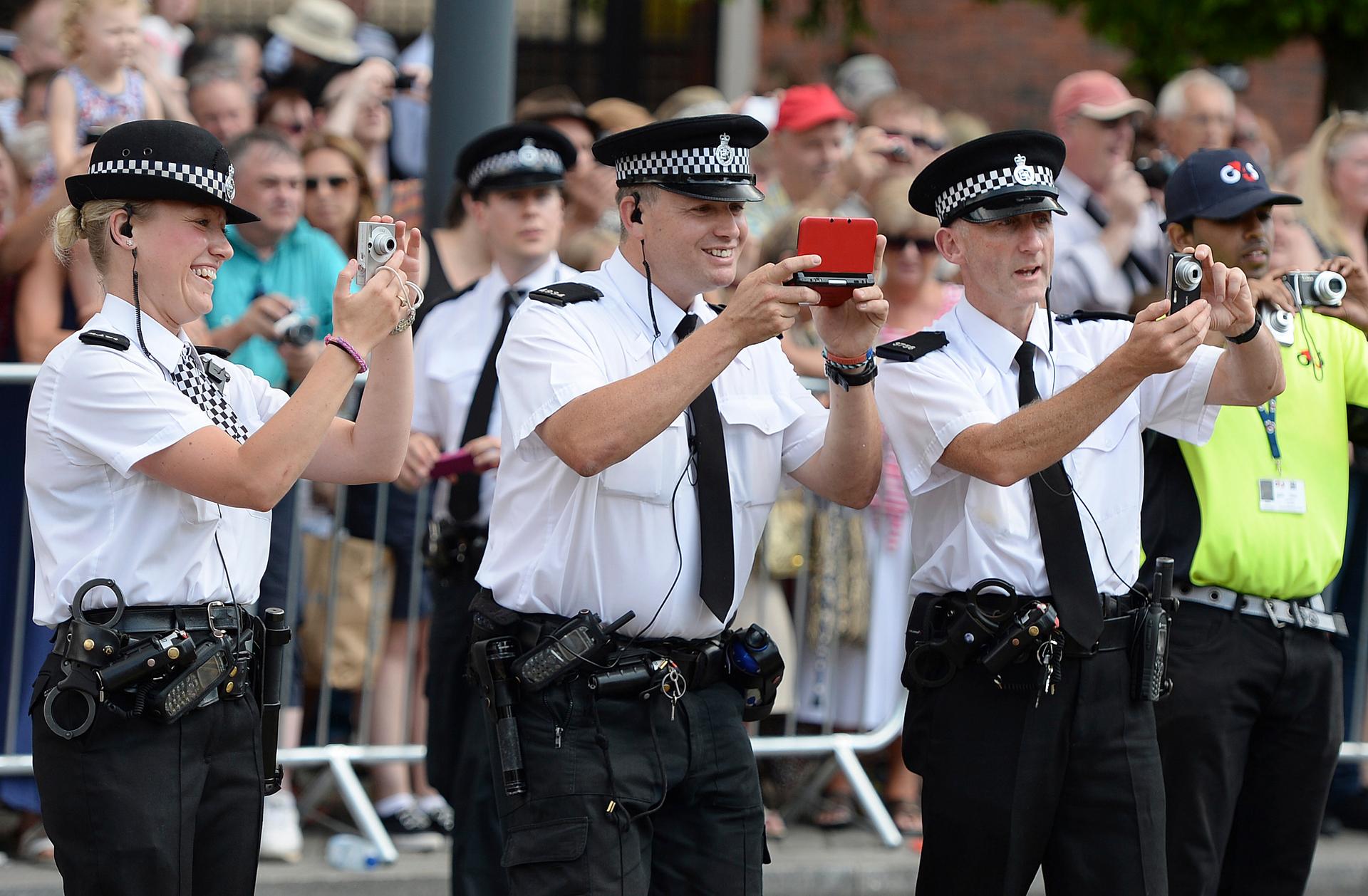 Police officers take pictures of giant puppets as they move through the streets of Liverpool, northern England July 25, 2014.