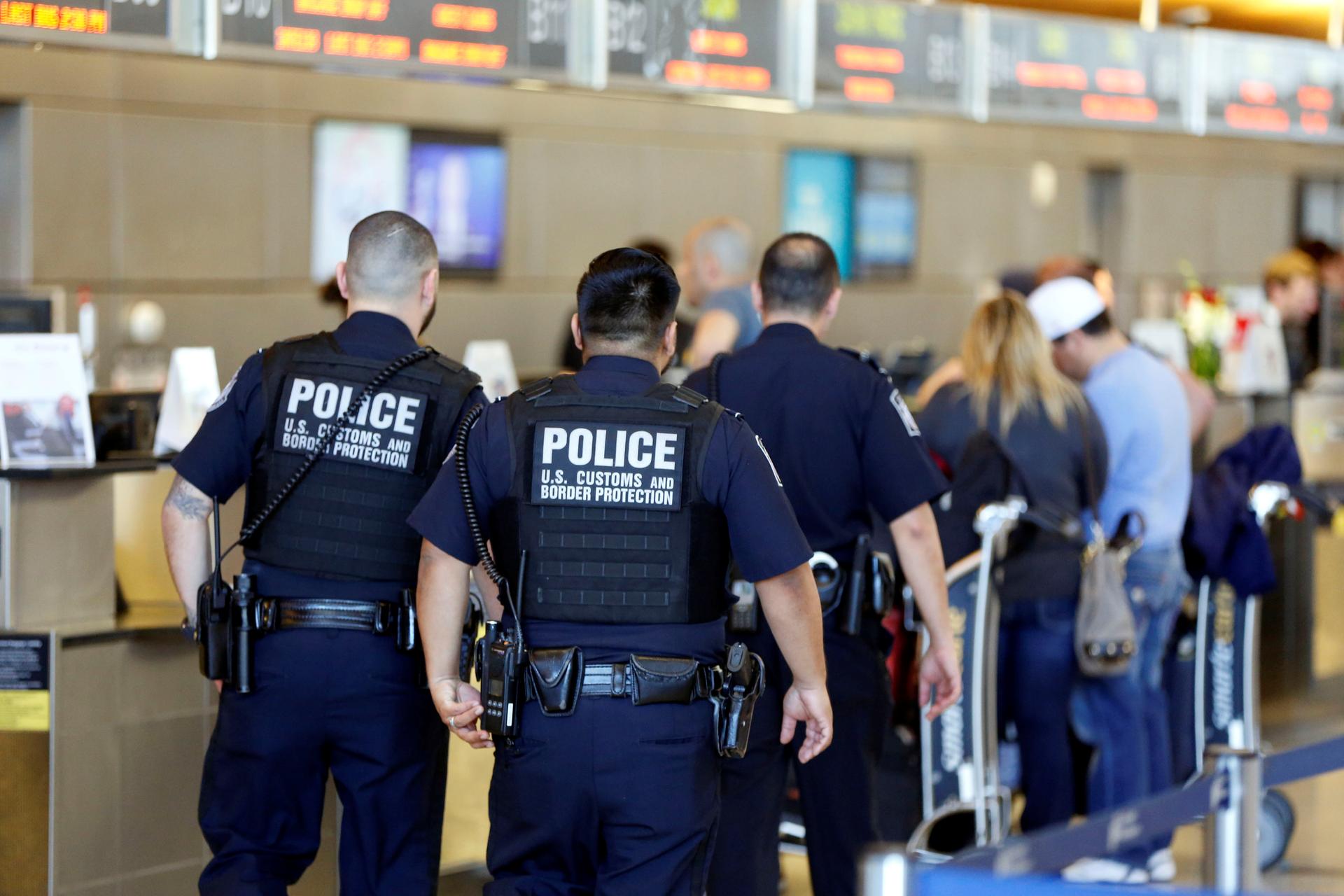 Officers with US Customs and Border Protection walk past ticket counters