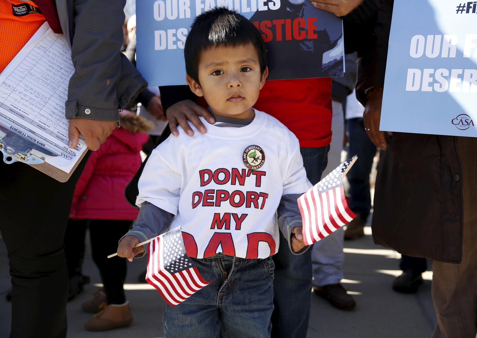 A young boy holds US flags as immigrants and community leaders rally in front of the U.S. Supreme Court to mark the one-year anniversary of President Barack Obama's executive orders on immigration in Washington, November 20, 2015.