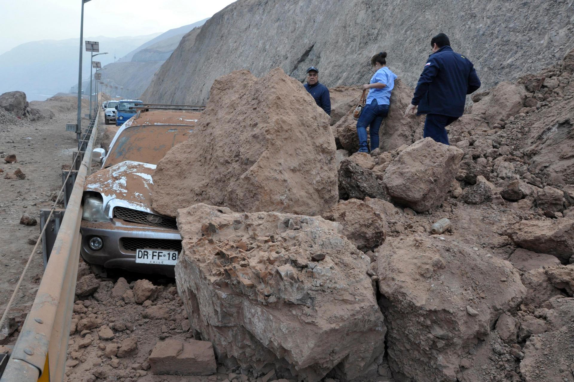Rescue workers inspect a car caught under a landslide after an earthquake and tsunami hit the northern port of Iquique, April 2, 2014. The earthquake, with a magnitude of 8.2, struck off the coast of northern Chile near the copper exporting port of Iquiqu