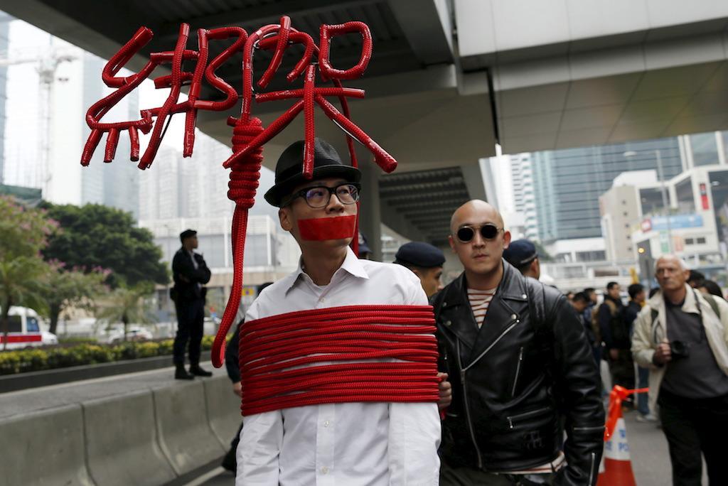An artist ties himself with a rope that spells out "Kidnap" during a protest over the disappearance of booksellers in Hong Kong, Jan. 10, 2016.