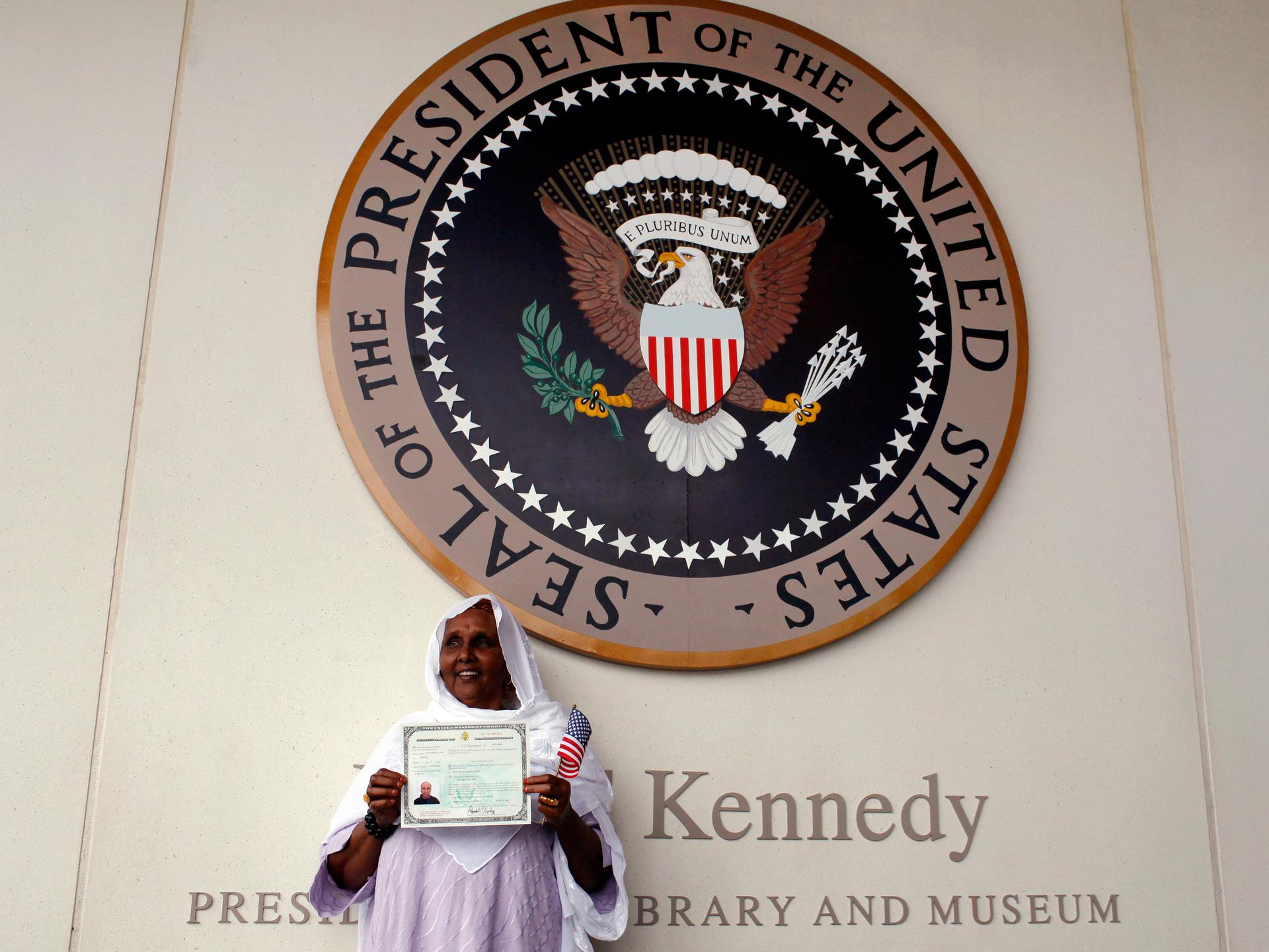 A woman holds up her certificate of U.S. citizenship