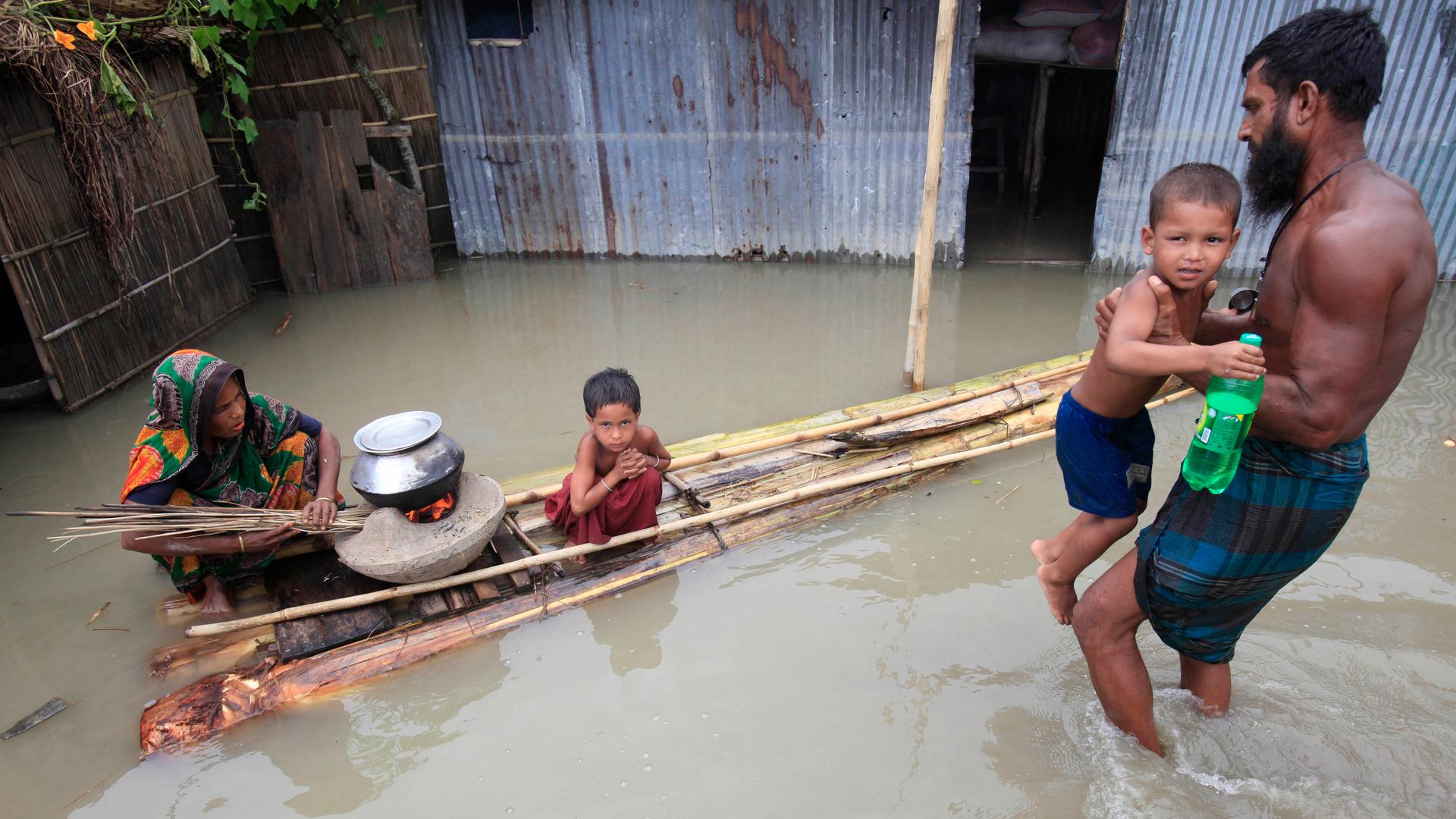 A woman cooks next to her child on a makeshift banana plant raft at a flooded village in Bangladesh July 3, 2012. Low-lying Bangladesh is perhaps the most vulnerable nation to the impacts of climate change. 