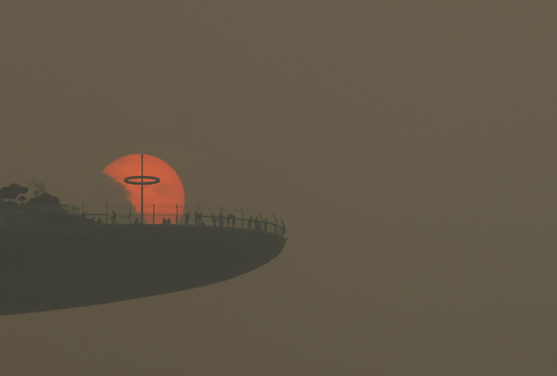 People watch the sun set through the pollution