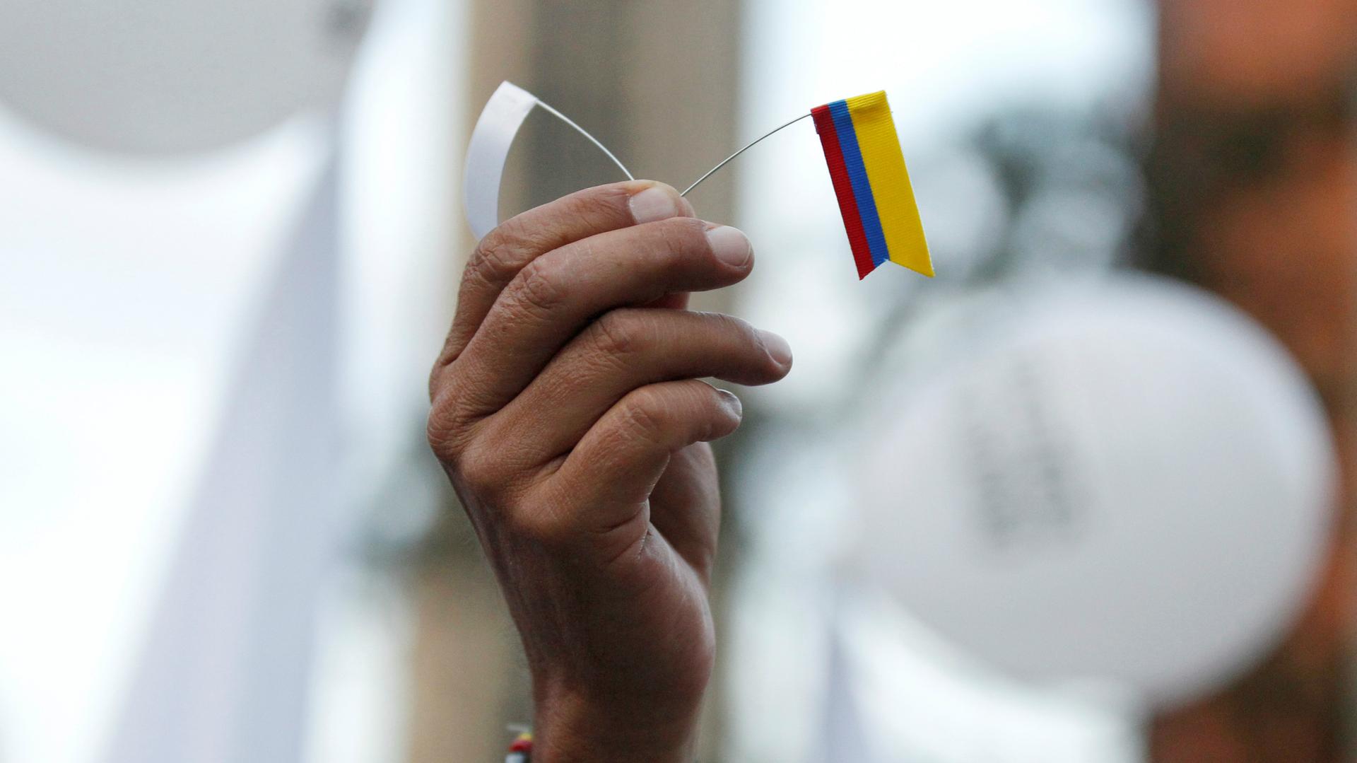 A demonstrator rallying in support of Colombia's peace agreement with the FARC holds a tiny flag during a march in Bogota, Colombia, on Nov. 15, 2016.