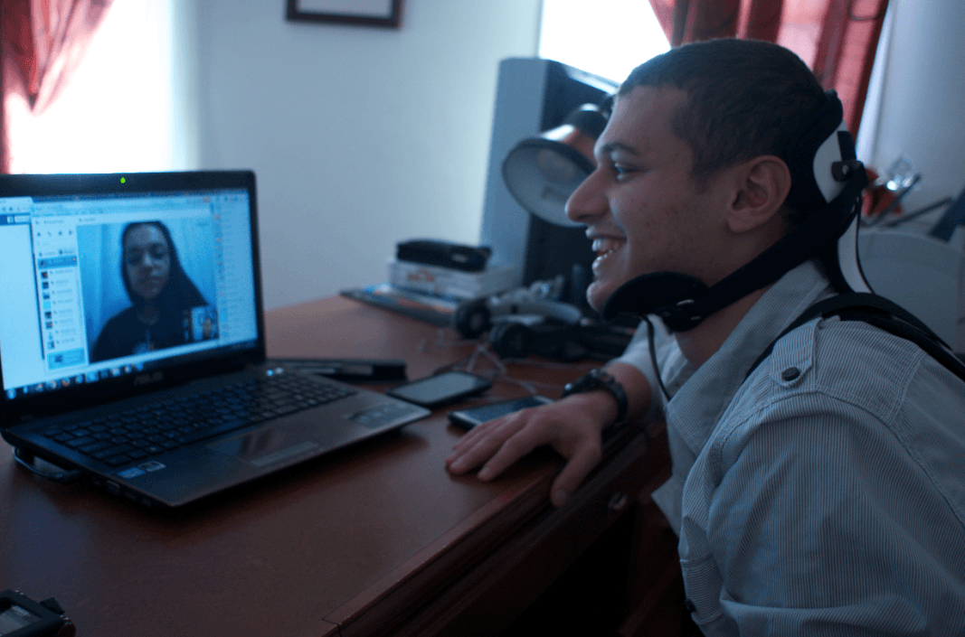 Fouad Faris, 19, sits at his computer in Shrewsbury, MA, video chatting with his sister, Rama, who is in Turkey. Faris wears a neck brace because he is recovering from a biking accident.
