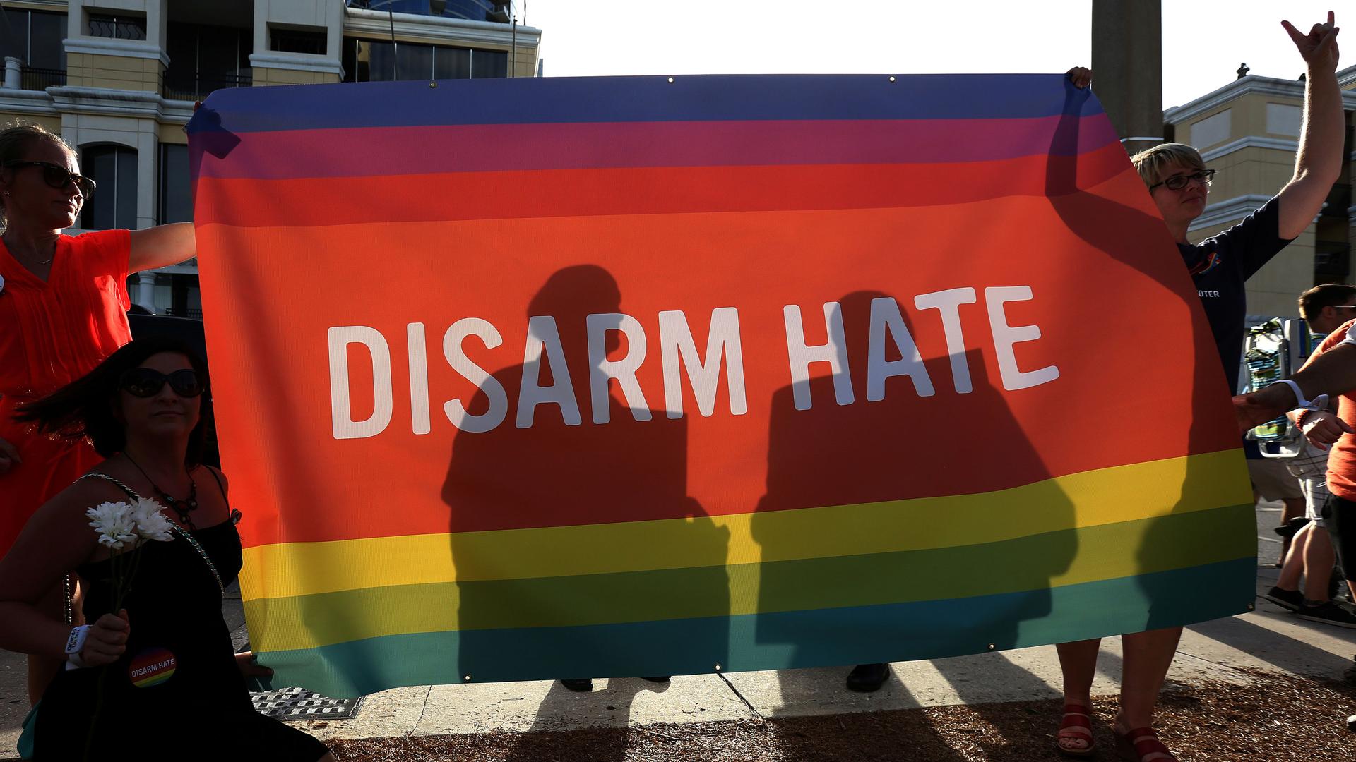 Supporters hold up a "Disarm Hate" sign to block protesters during a vigil for the Pulse night club victims following the shooting in Orlando, Florida, U.S., June 19, 2016.