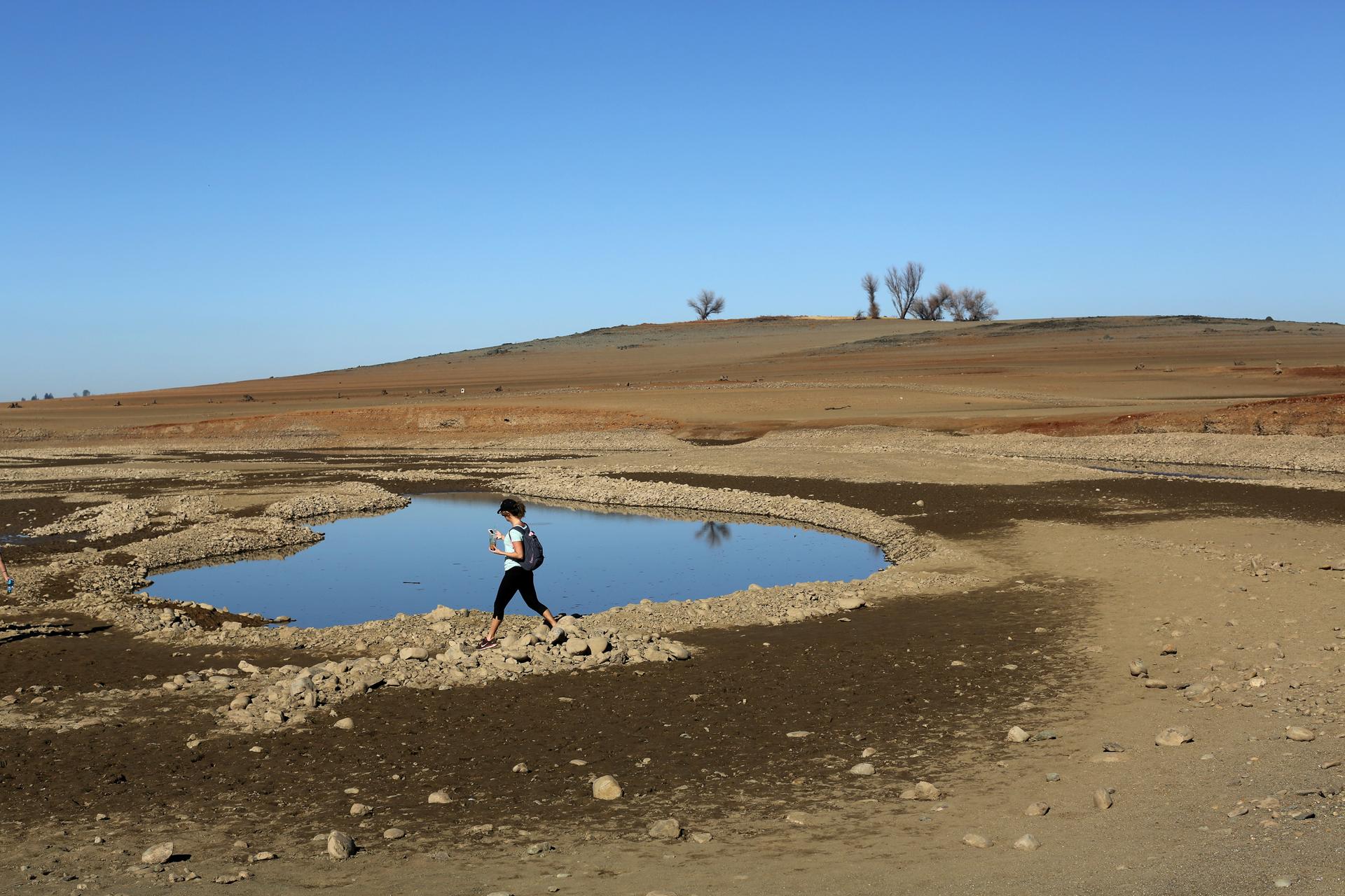 A visitor walks near the receding waters at California's Folsom Lake, which is at 17 percent of its capacity, On April 1, California Governor Jerry Brown announced unprecedented mandatory water restrictions and ordered the State Water Resources Board to r