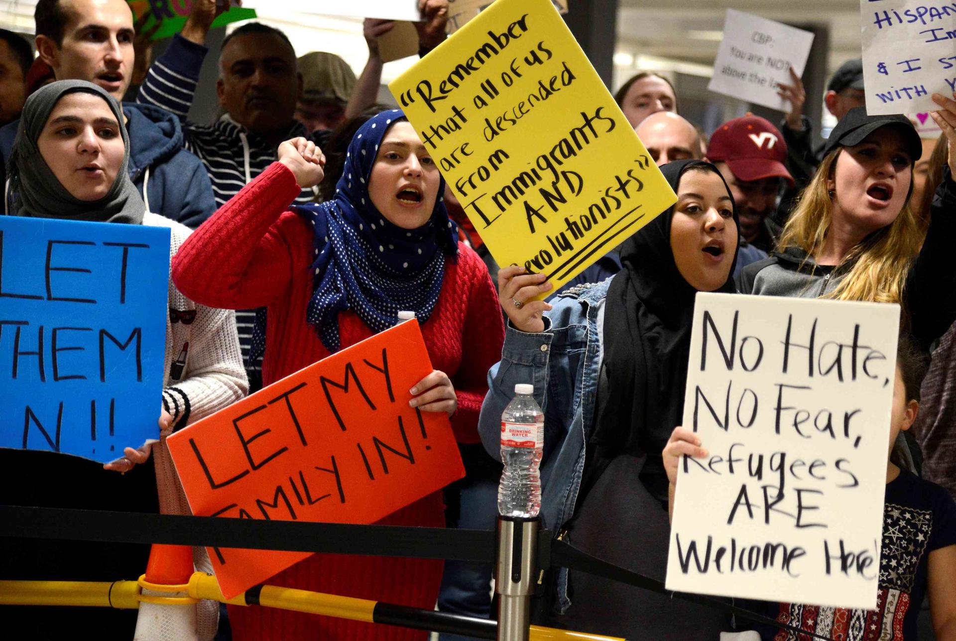 Dozens of pro-immigration demonstrators cheer and hold signs as international passengers arrive at Dulles International Airport