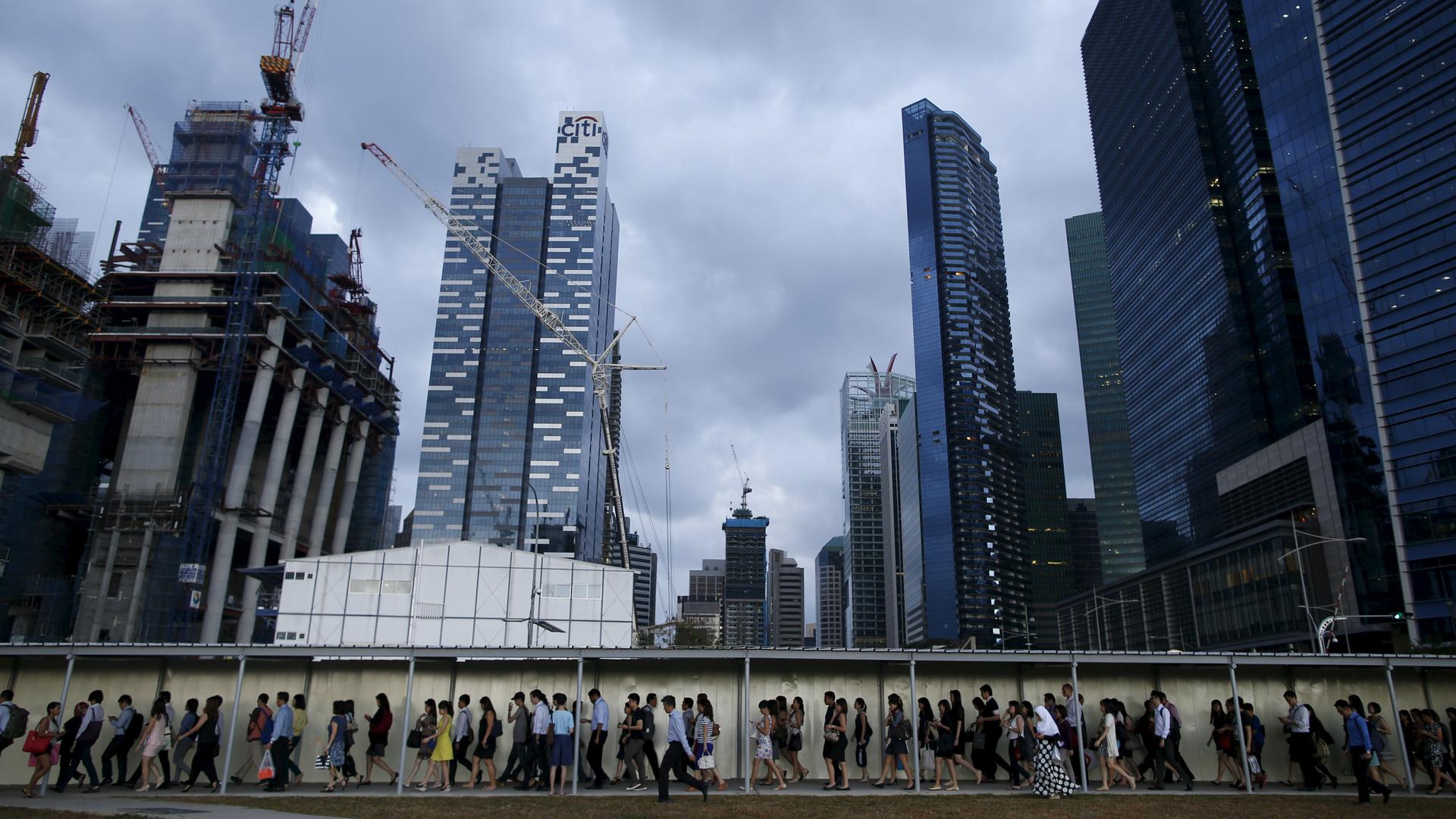 Commuters walk to the train station during evening rush hour in the financial district of Singapore March 9, 2015.