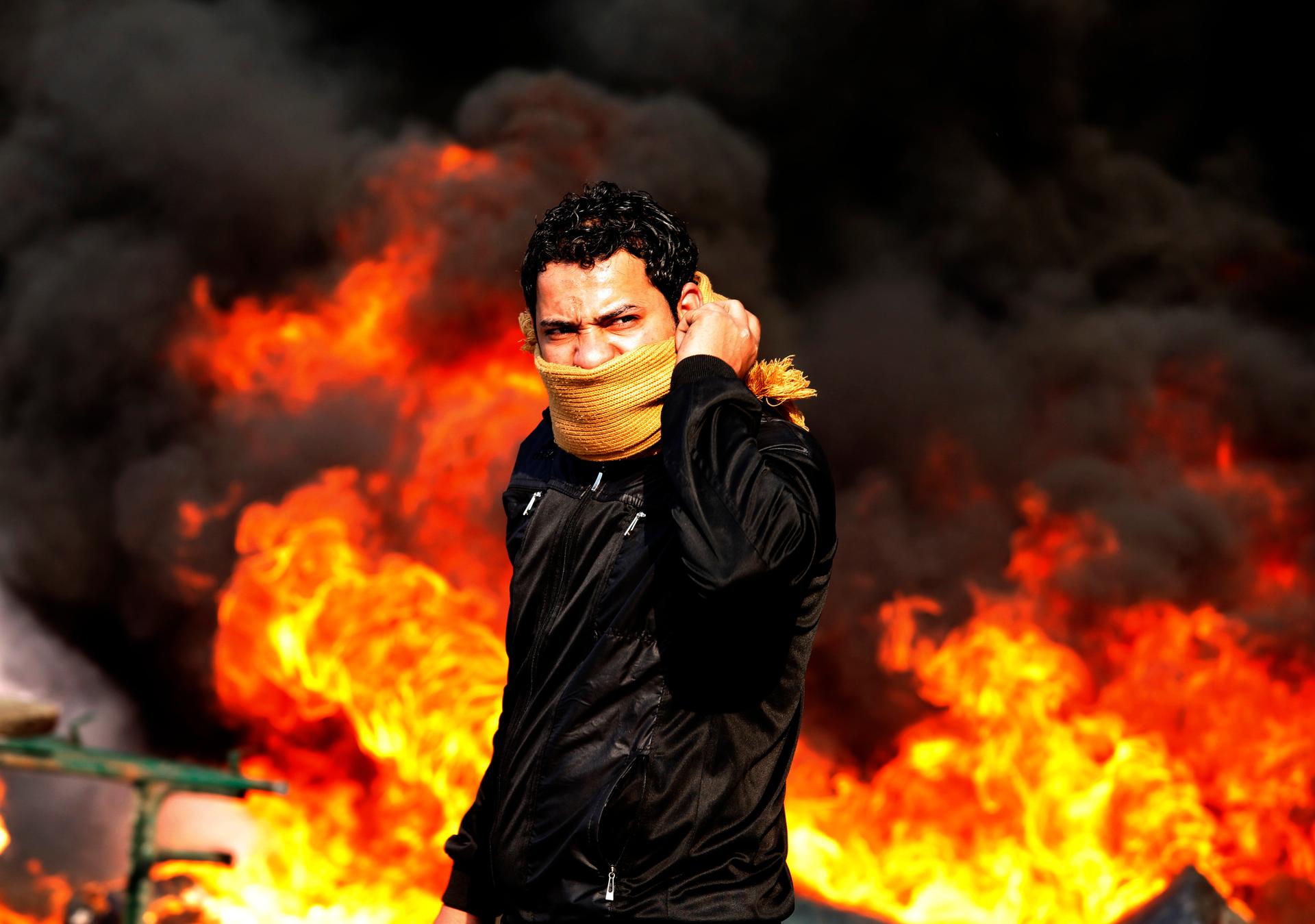 A protester stands in front of a burning barricade during a demonstration in Cairo January 28, 2011.