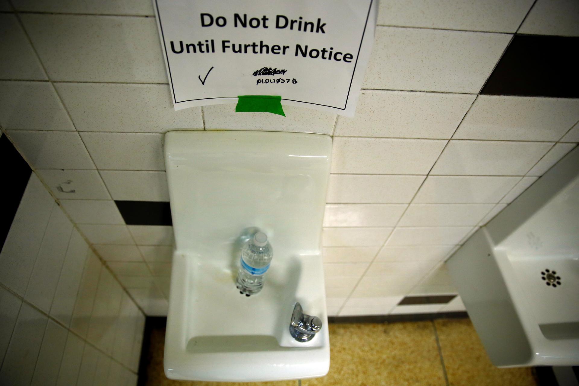 A sign is seen next to a water dispenser at a high school in Flint