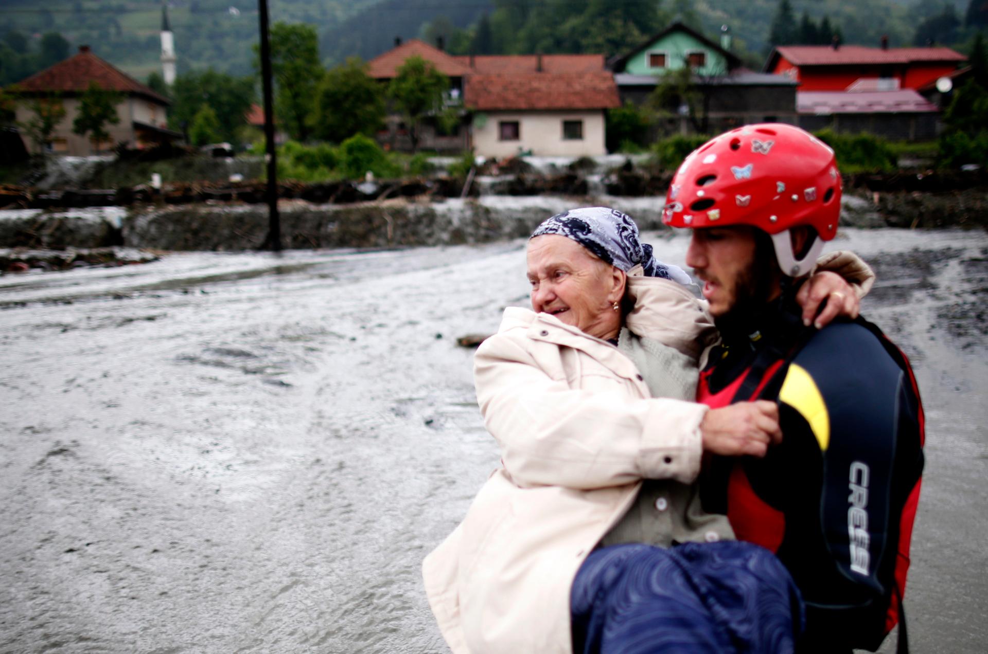 A member of the rescue team carries a women as they leave her flooded house in Topcic Polje, near Zepce May 16, 2014. The heaviest rains and floods in 120 years have hit Bosnia and Serbia.