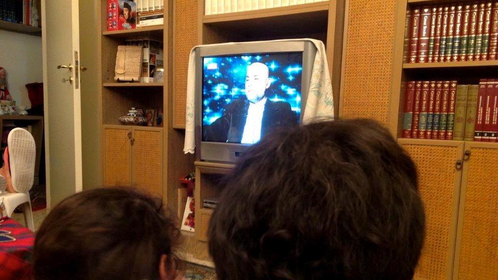A Lebanese family watches TV fortune teller Mike Feghaly give his predictions for 2014