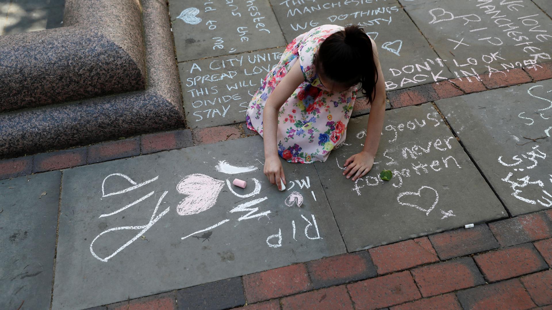 A girl writes a message in chalk on the pavement in central Manchester, Britain.