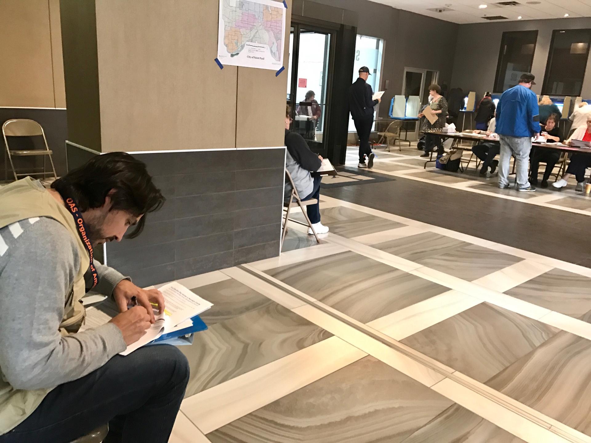 Man sits in polling place with binder