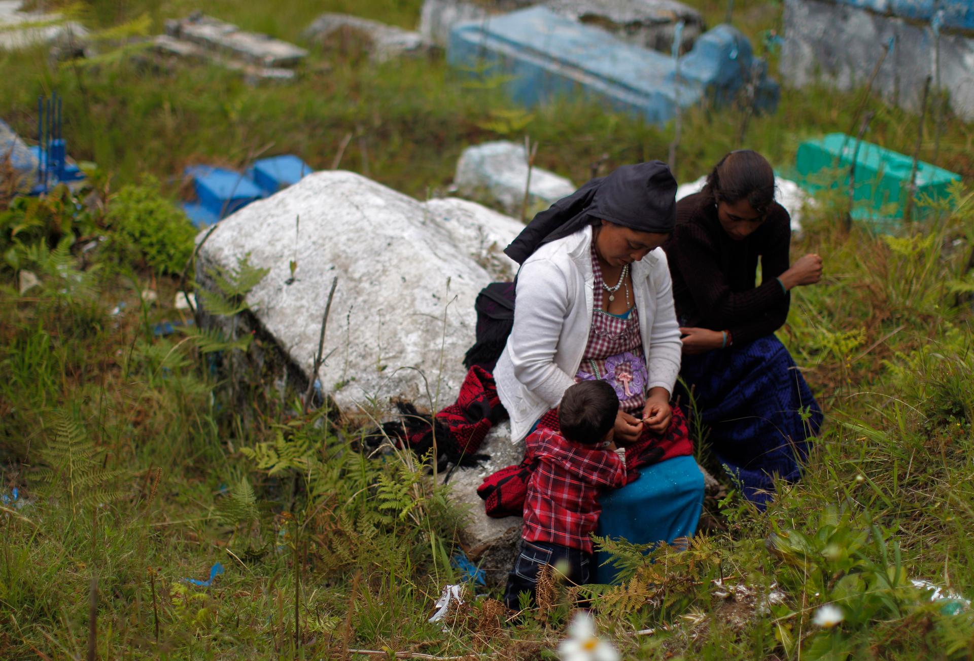 A women and a child sit near a grave for the body of teenage migrant Gilberto Francisco Ramos Juarez, at a cemetery in San Jose Las Flores, north of Guatemala City, July 12, 2014. Ramos Juarez's body was found in the Rio Grande Valley of southern Texas, l
