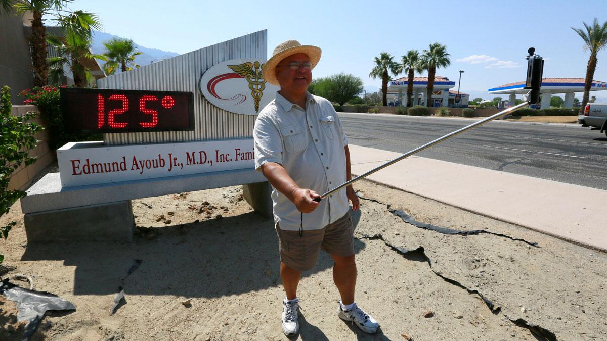 Palm Springs resident Benito Almojuela takes a selfie near a thermometer sign which reads 125 degrees in Palm Springs, California, June 20, 2016.