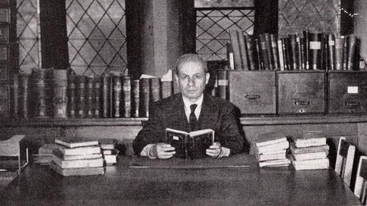 Black and white photo of man at table, with books
