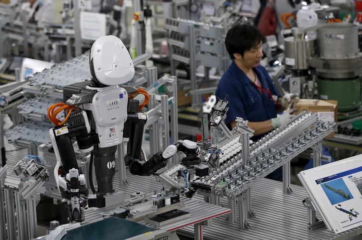 A robot with human-like features works on an assembly line beside a human worker at a factory of Glory Ltd., a manufacturer of automatic change dispensers, in Kazo, north of Tokyo, Japan, July 1, 2015.