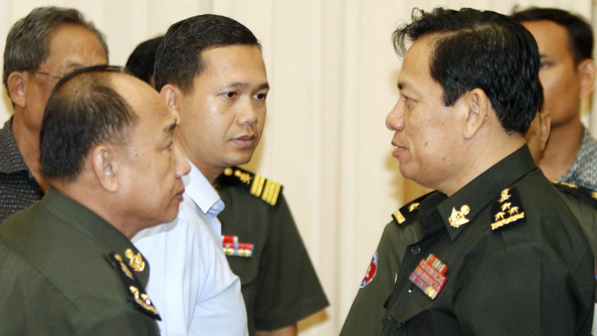 Hun Manet (C), son of Cambodia's Prime Minister Hun Sen, looks at Cambodia's Defense Ministry spokesman Chhum Socheat (R), after a news conference at the Council of Ministers in Phnom Penh April 22, 2011