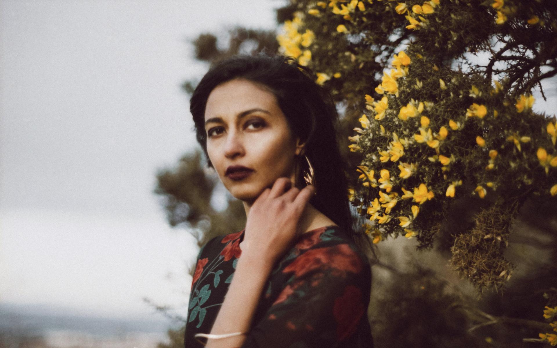 Artist Lakshmi Ramgopal poses in front of yellow flowers in this 2017 photograph.