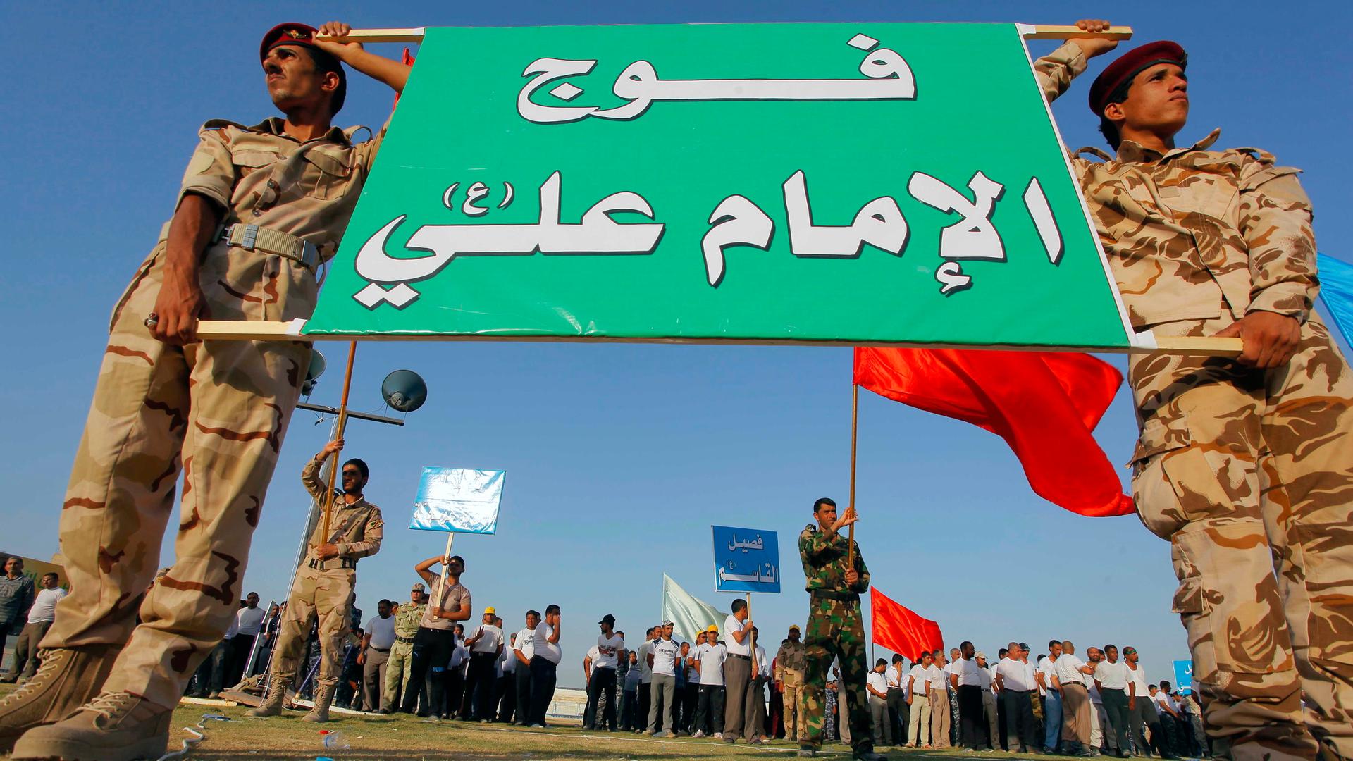 Shi'ite volunteers, who have joined the Iraqi army to fight against the predominantly Sunni militants from the radical Islamic State of Iraq and Syria (ISIS), hold a sign during a graduation ceremony after completing their field training in Najaf, that re
