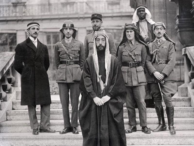 Left to right: Rustum Haidar, Nuri as-Said, Prince Faisal (front), Captain Pisani (rear), T. E. Lawrence, Faisal's slave (name unknown), Captain Hassan Khadri.
