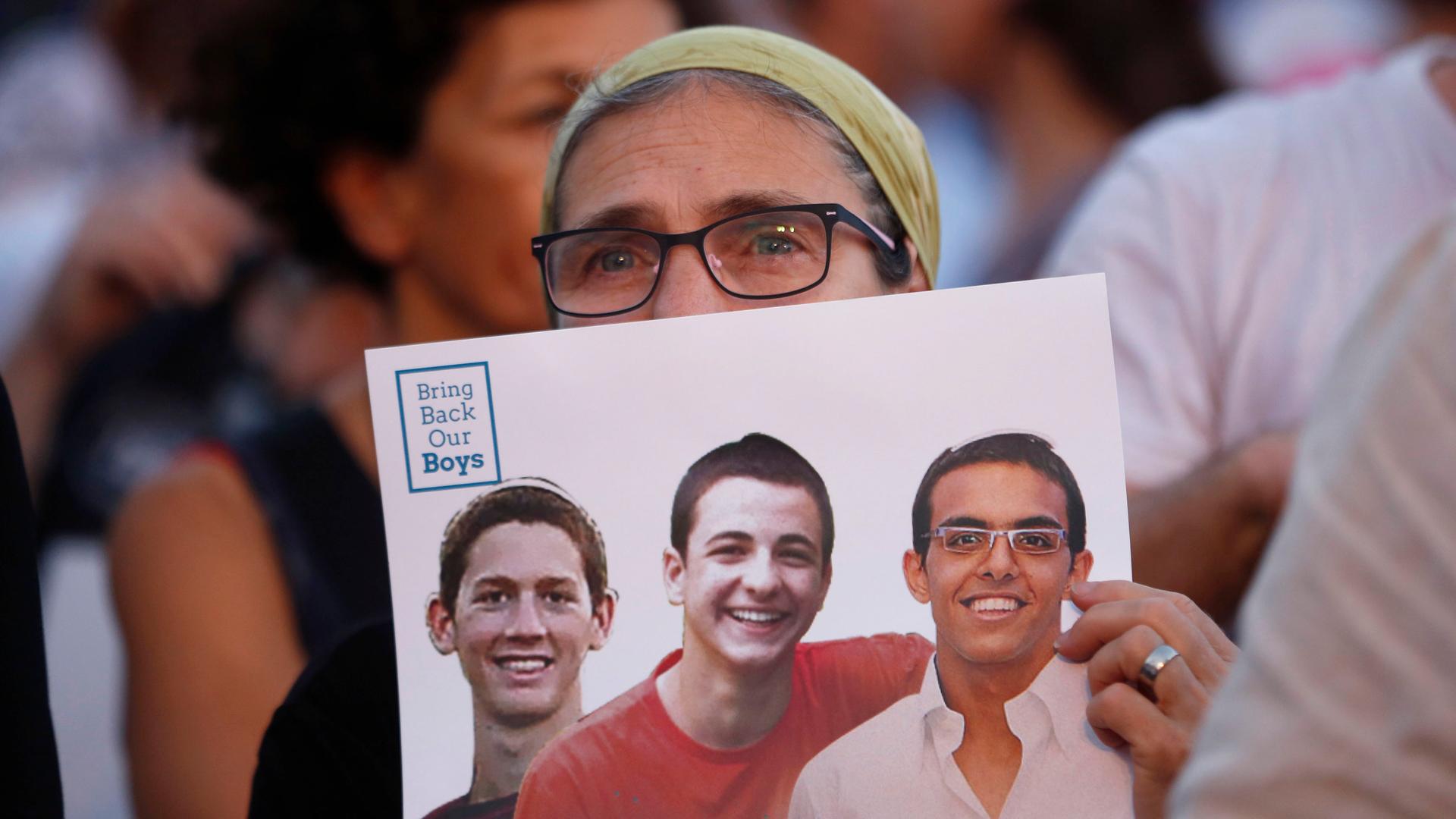 An Israeli woman holds a sign with images of three missing Israeli teenagers, at a rally in Rabin Square in the coastal city of Tel Aviv June 29, 2014. Israel on Thursday named two Hamas Islamists as leading suspects in the June 12 kidnappings of the thre