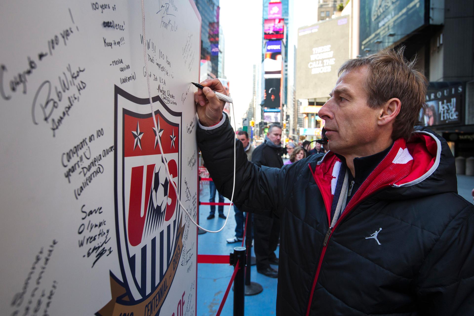 German soccer star Jurgen Klinsmann, the coach of the US men's national team, signs a board celebrating the 100th anniversary of the US national team in Times Square, April 4, 2013.