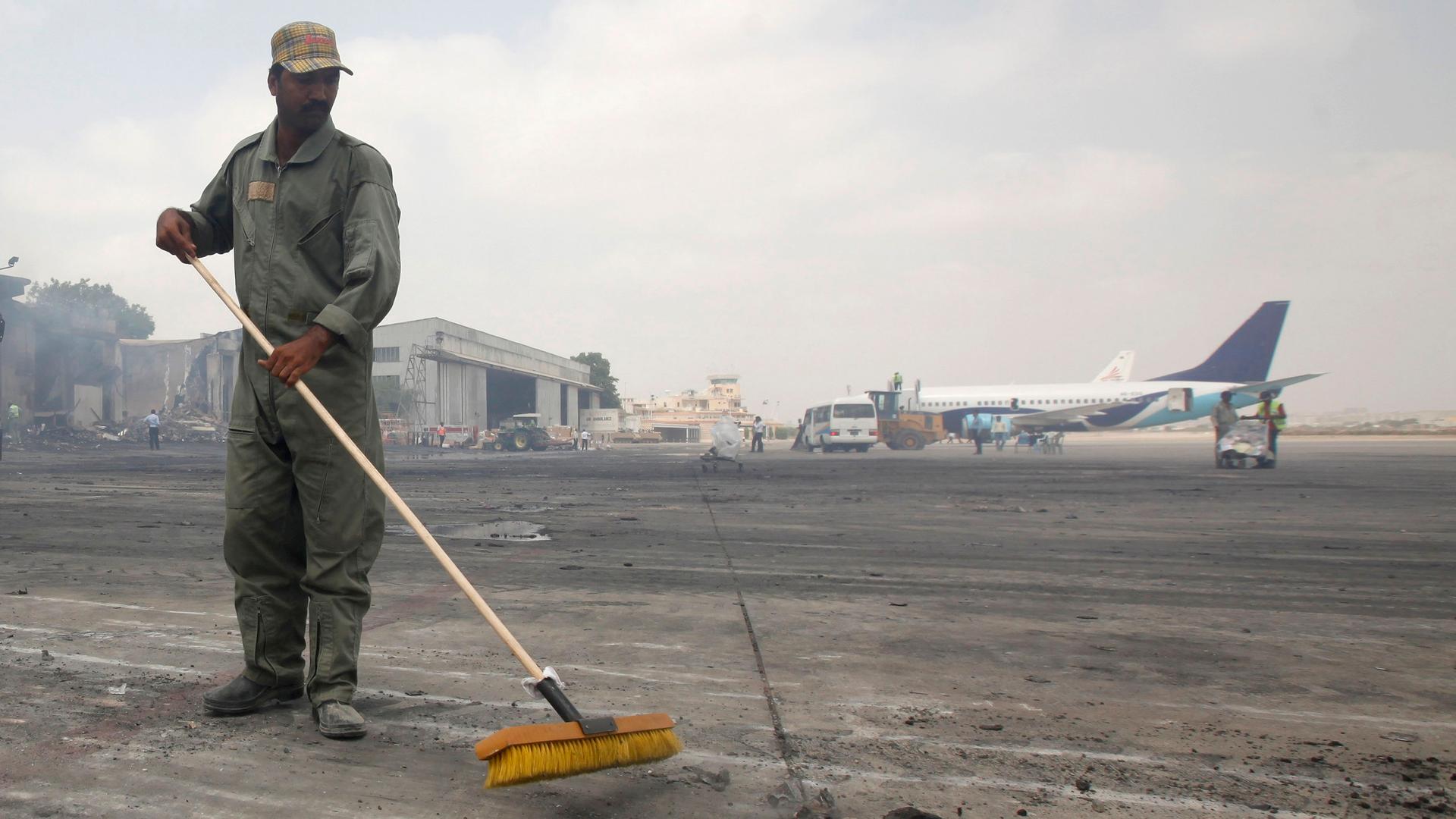 A man clears debris from the tarmac of Jinnah International Airport, after Sunday's attack by Taliban militants on Sunday, in Karachi June 10, 2014. Taliban militants disguised as security forces stormed into Pakistan's busiest airport on Sunday night, tr