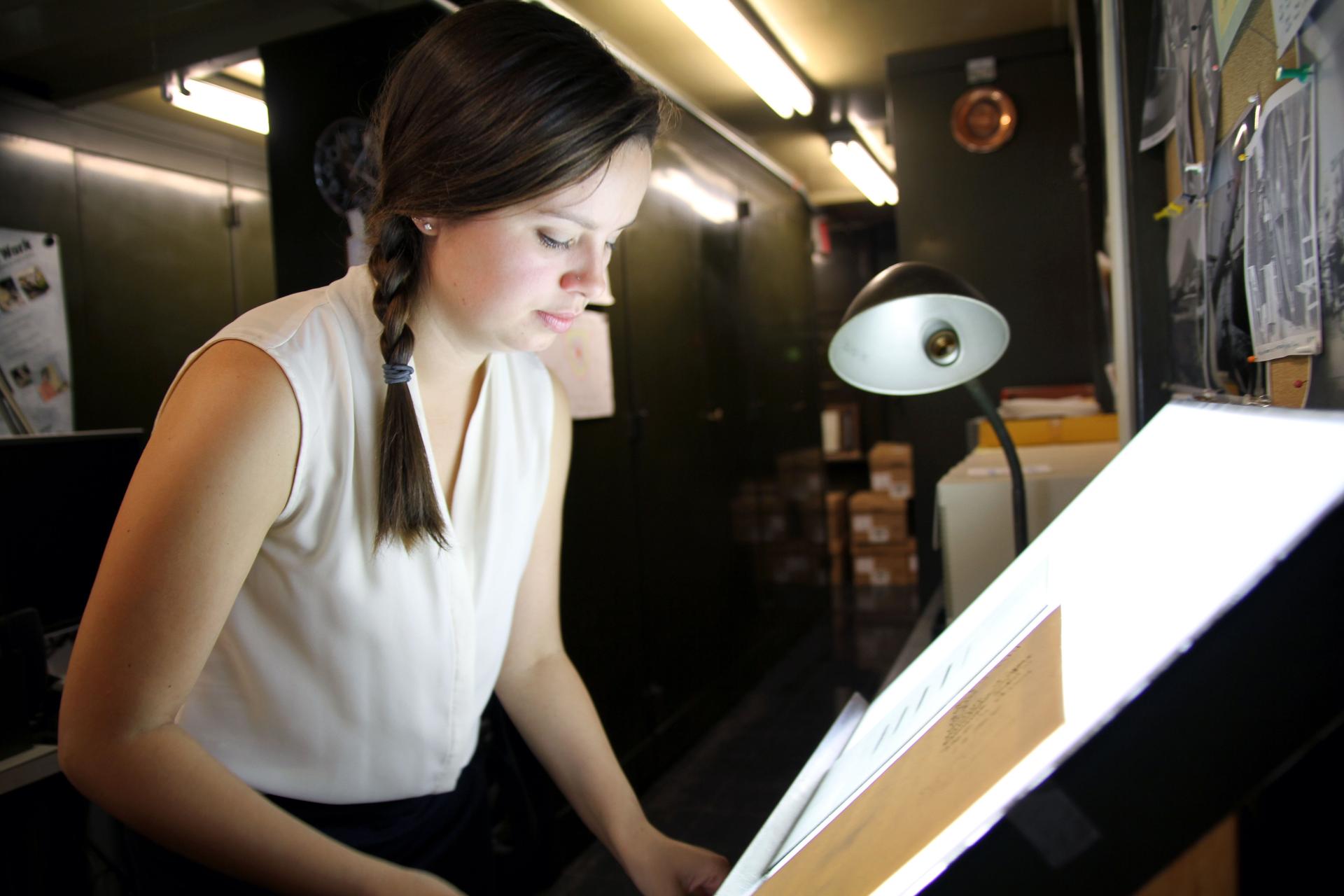 Lindsay Smith Zrull carefully places a glass plate photograph of the sky on a lightbox in the Plate Stacks room at the Harvard-Smithsonian Center for Astrophysics.