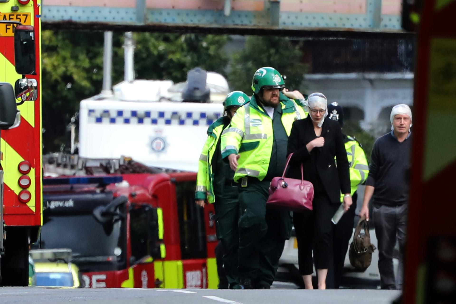 An injured woman is led away after an incident at Parsons Green underground station