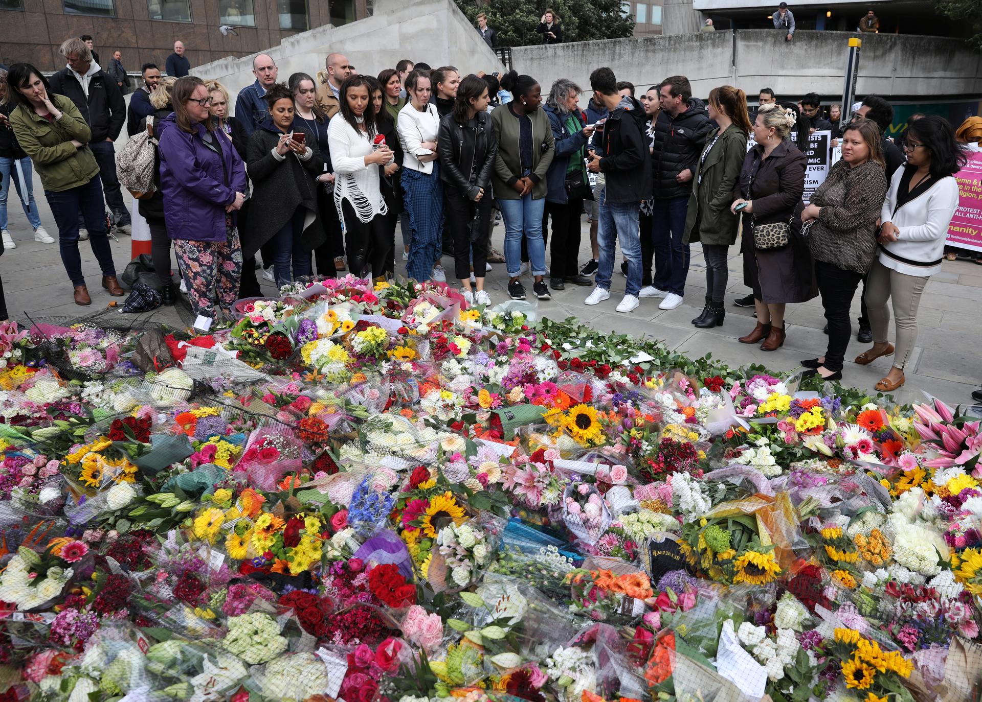 People look at floral tributes for the victims of the attack on London Bridge and Borough Market near the scene of the attack, London, June 6, 2017.