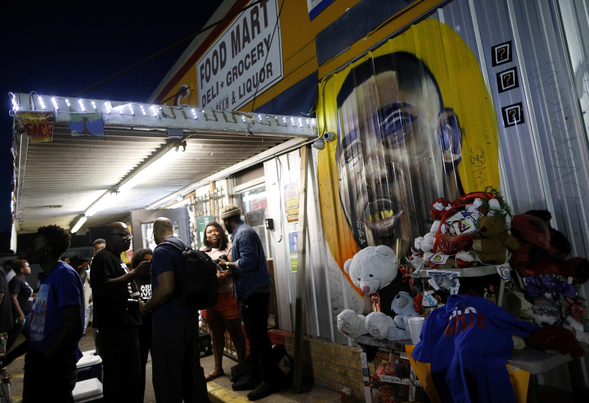 A mural of Alton Sterling is seen as people gather during a vigil