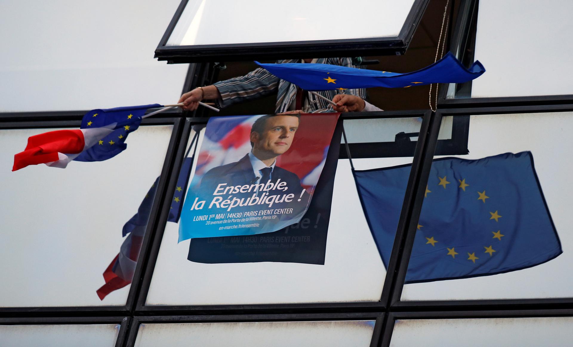 A supporter holds a campaign poster of Emmanuel Macron and European Union flags