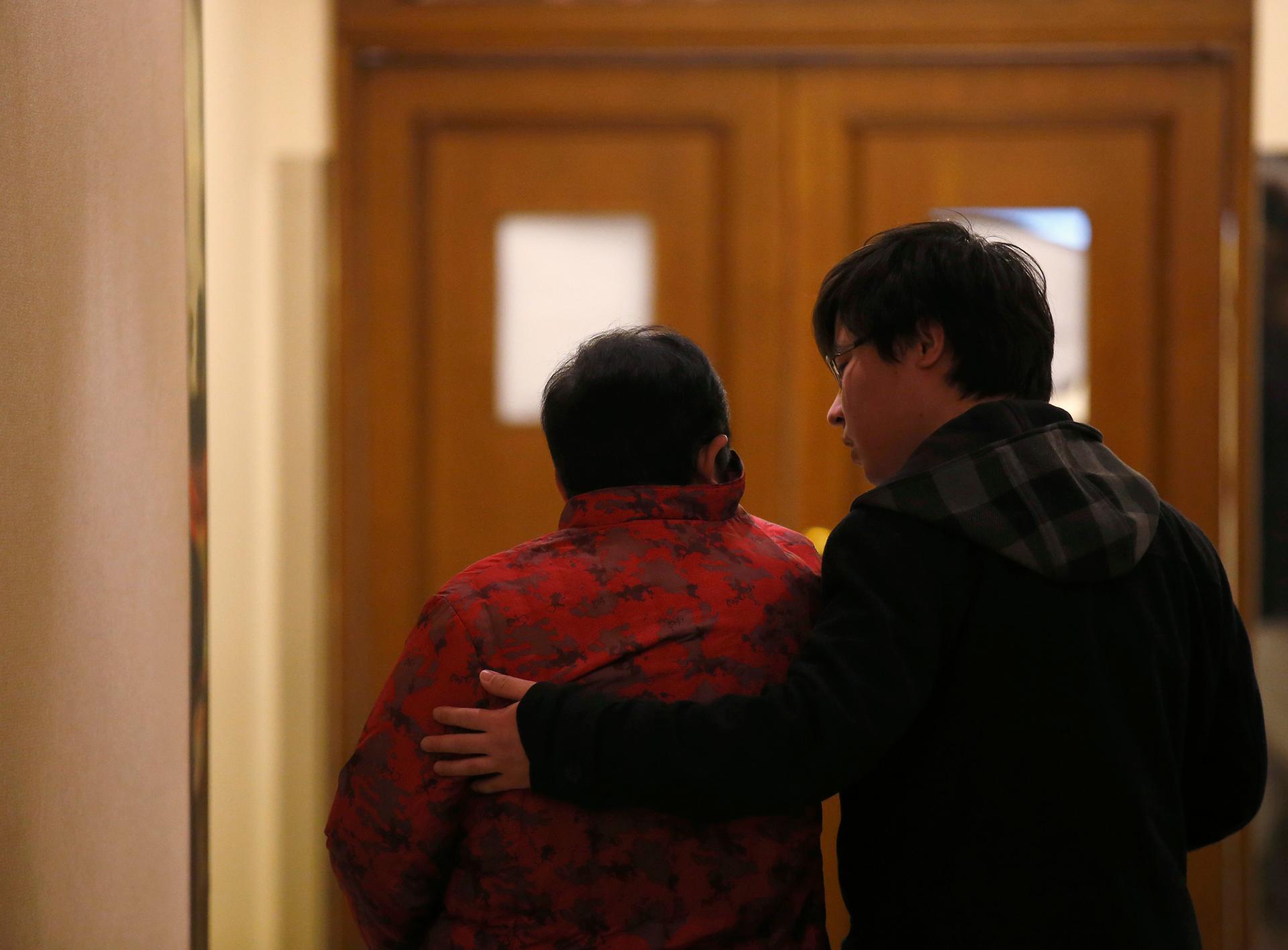 A man comforts a family member of a passenger onboard the missing Malaysia Airlines flight MH370 as they wait for news from Malaysia Airlines, at the lobby of a hotel in Beijing, March 14, 2014.