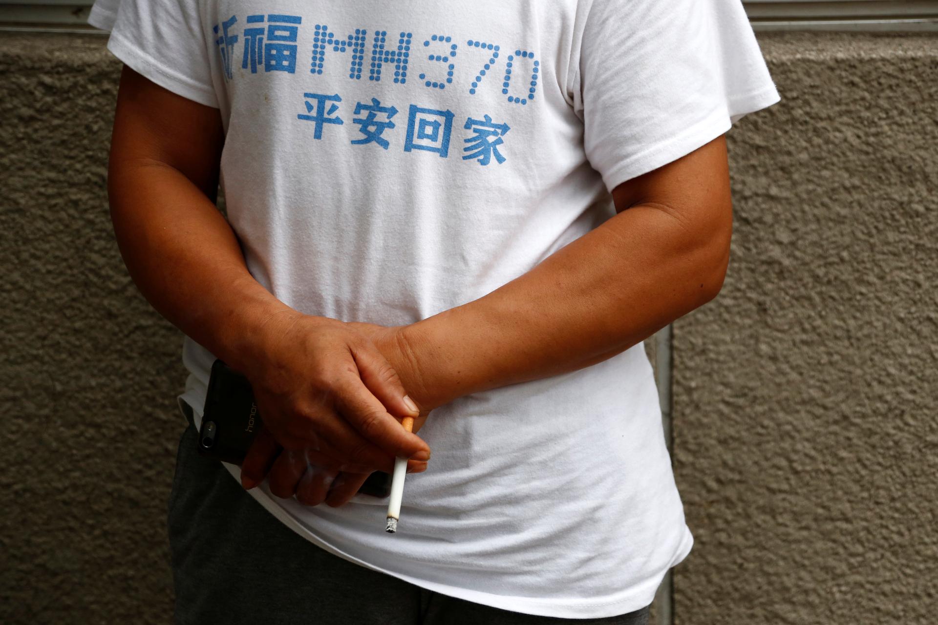 A man surnamed Lee who said his son was aboard the Malaysia Airlines flight MH370 that went missing in 2014 smokes during a protest outside the Chinese foreign ministry