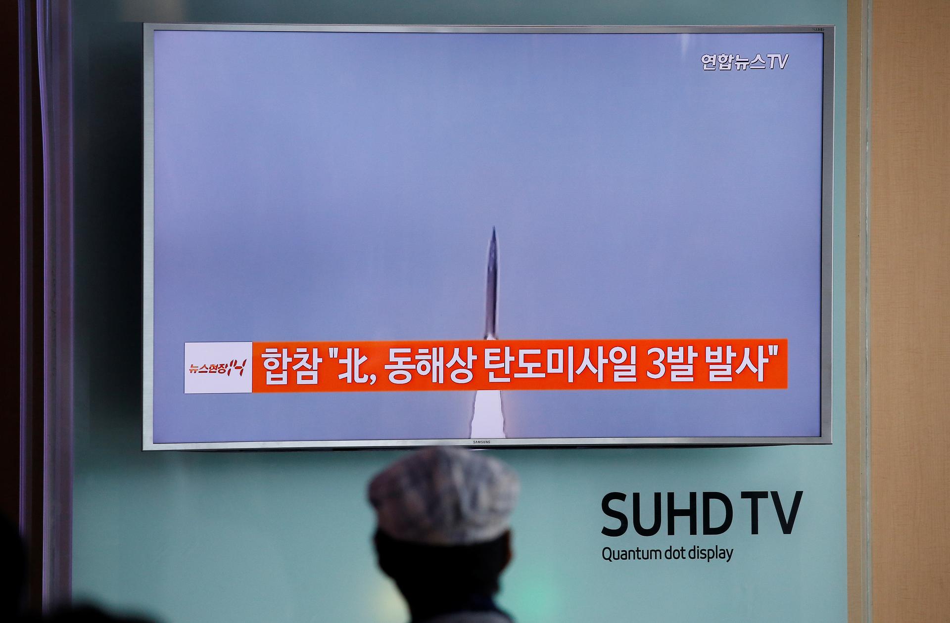 A passenger watches a TV screen broadcasting a news report on North Korea