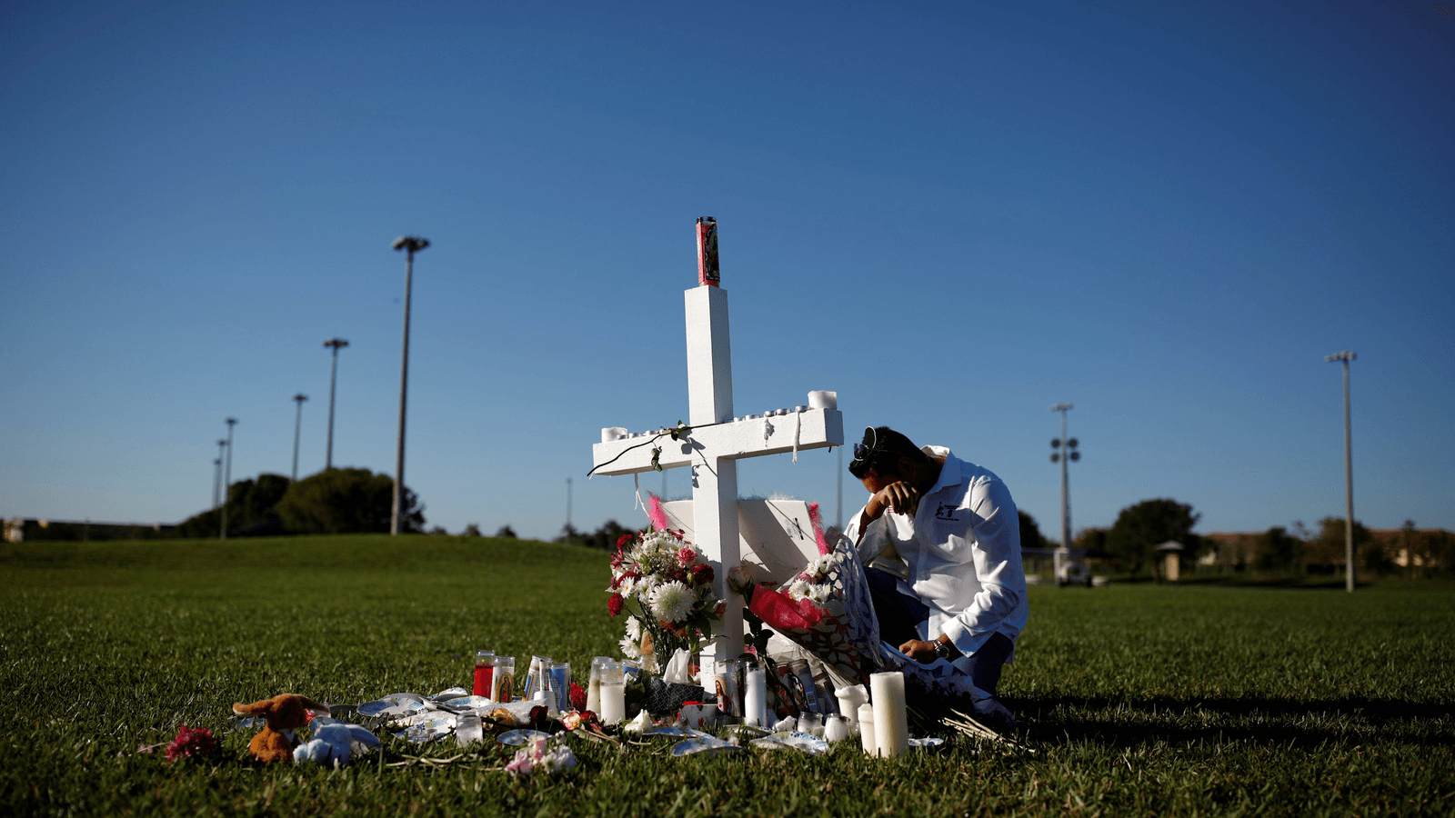 Joe Zevuloni mourns in front of a cross placed in a park to commemorate the victims of the shooting at Marjory Stoneman Douglas High School, in Parkland, Florida, Feb. 16, 2018.