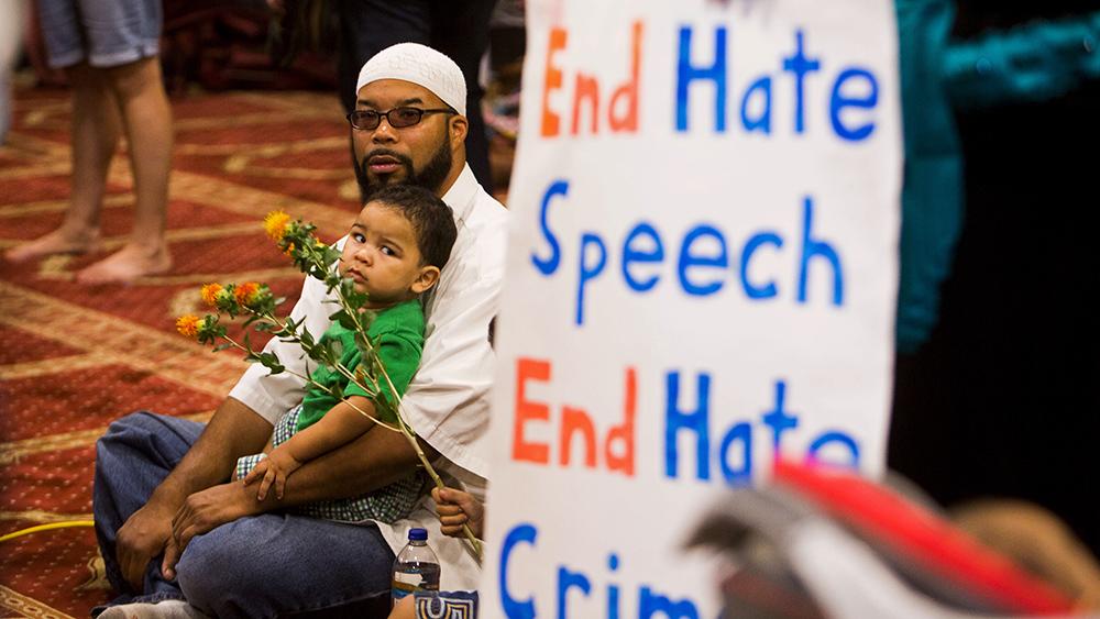 Attendees sit next to a poster as speakers from different faiths speak at an interfaith rally titled "Love is Stronger than Hate" at the Islamic Community Center in Phoenix. The rally was held in response to an earlier anti-Muslim rally at the same locati