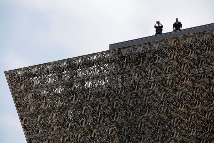 Two Secret Service agents stationed on the roof of the National Museum of African American History and Culture use binoculars to survey the crowd during the Museum's opening ceremony on September 24, 2016.