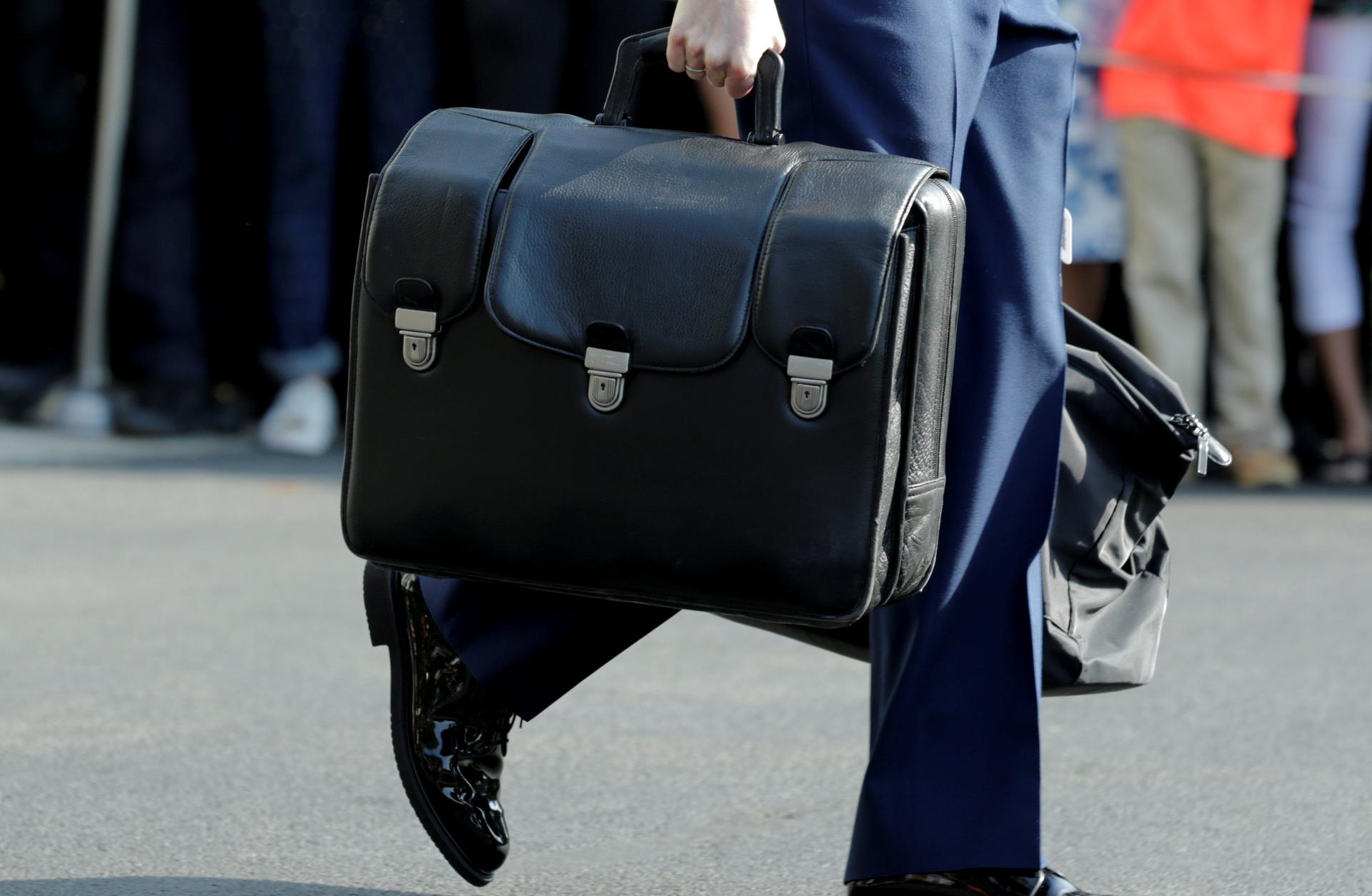 A military aide carrying a briefcase containing nuclear codes follows President Barack Obama on the South Lawn of the White House in Washington, DC, before his departure to Miami, Oct. 20, 2016.