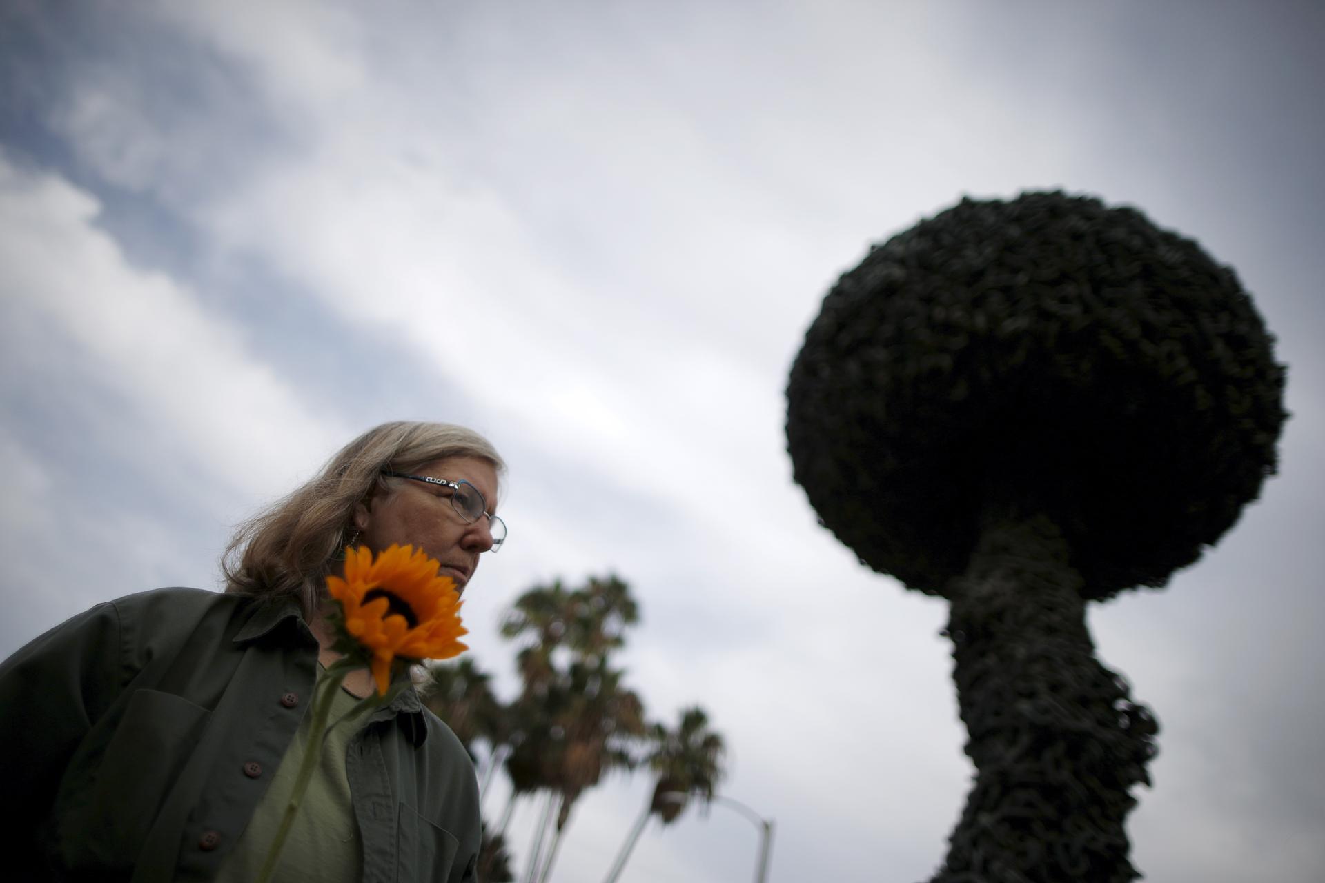 Patricia Todd, 61, holds a sunflower at a peace vigil in front of "Chain Reaction," a mushroom cloud sculpture created by Paul Conrad as a symbol of a world free of nuclear weapons, in Santa Monica, California, United States, September 21, 2015. 