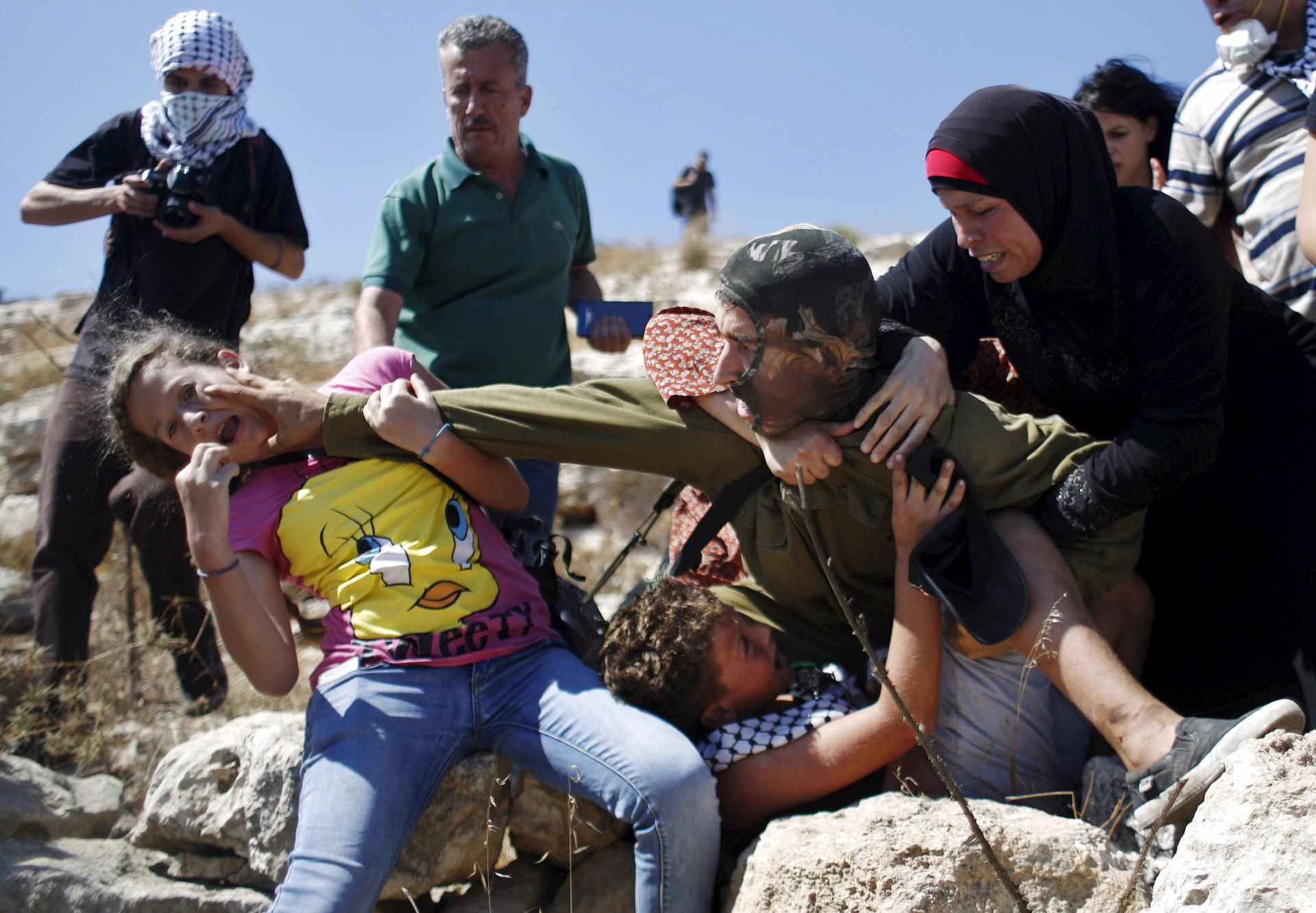 Palestinians scuffle with an Israeli soldier
