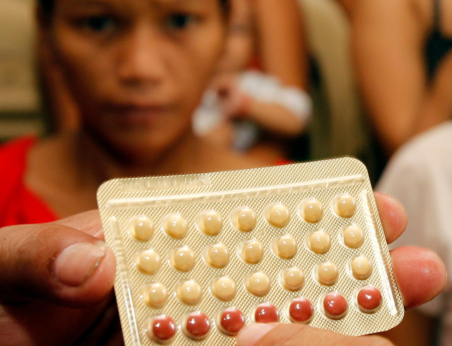 An NGO health worker holds contraceptive pills
