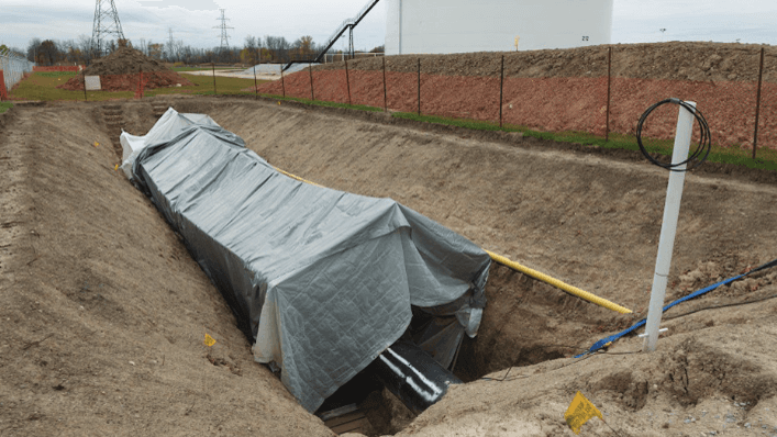 A section of Enbridge pipeline lies under a cover in a trench.